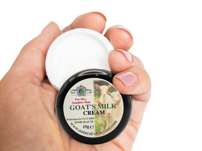 Hand holding a small jar of 15g goat's milk cream with a white background
