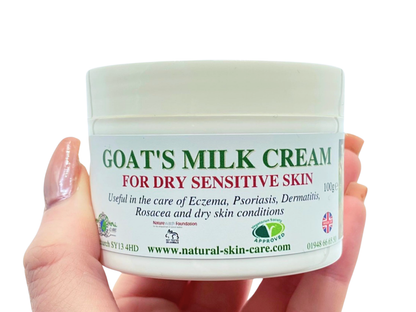 Jar of goat's milk cream for dry sensitive skin held by a hand on a white background